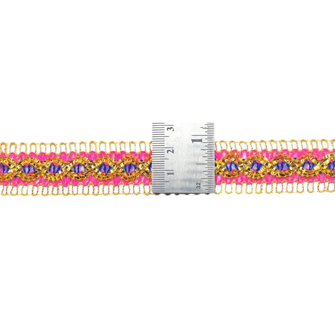 Gold and pink beaded trim with a ruler for scale on a white background